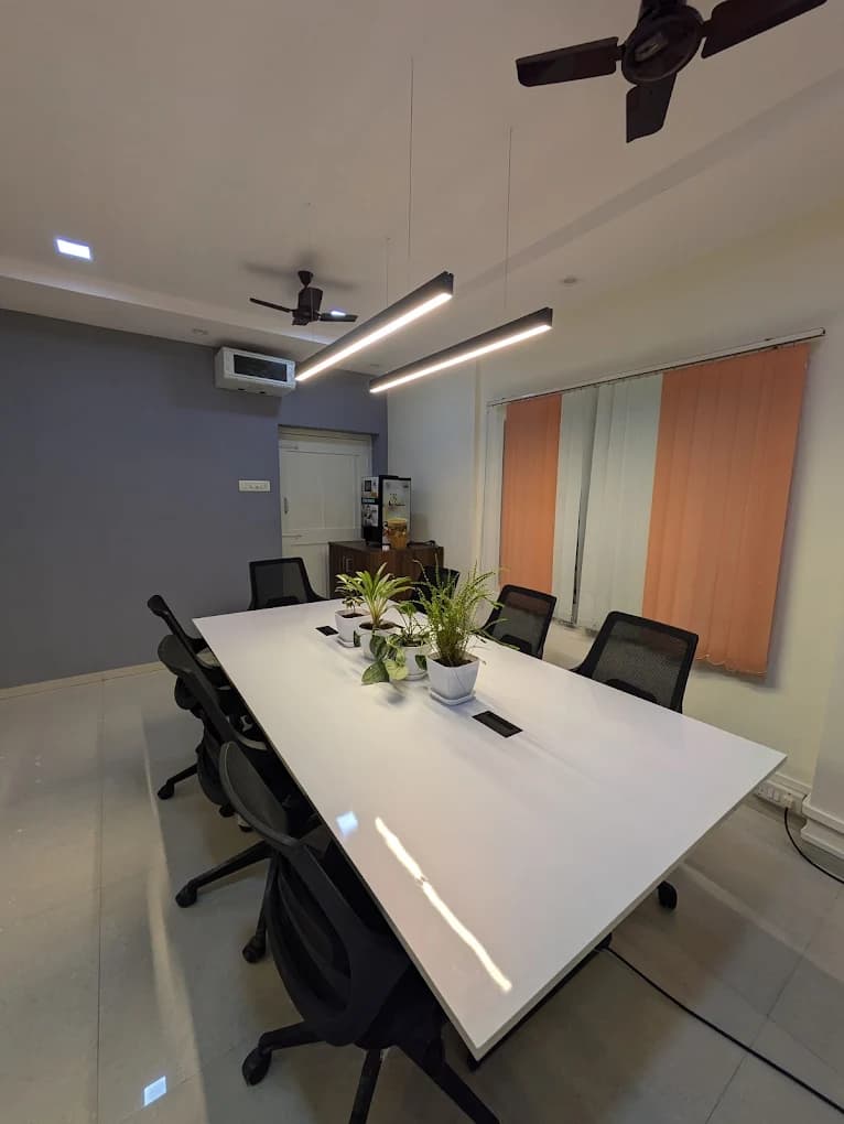 Conference table at the Full Stack World Vizag campus, with pendant lighting, plants and ergonomic chairs