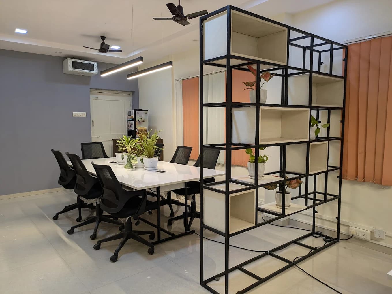 Wide view of the Full Stack World studio in Vizag, with meeting table, ergonomic seating and a feature bookshelf divider