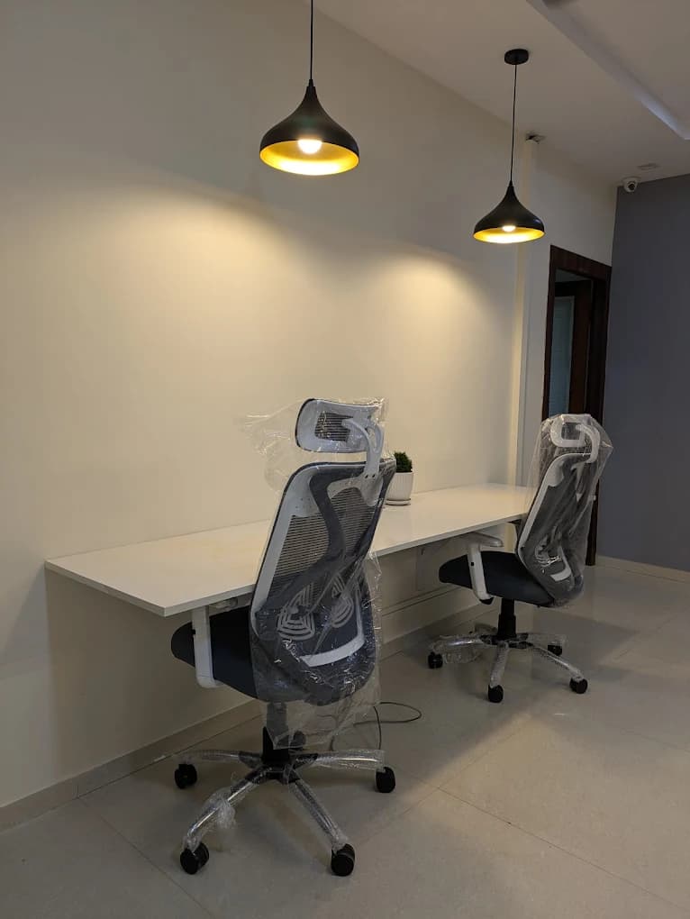 Two-seat workstation desk with ergonomic chairs and pendant lights at the Full Stack World studio
